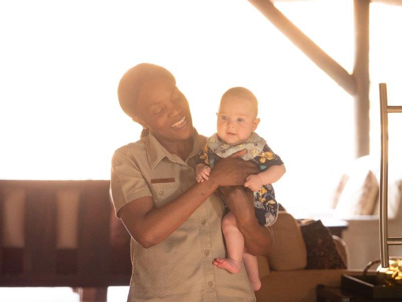 African lady holding baby at safari lodge